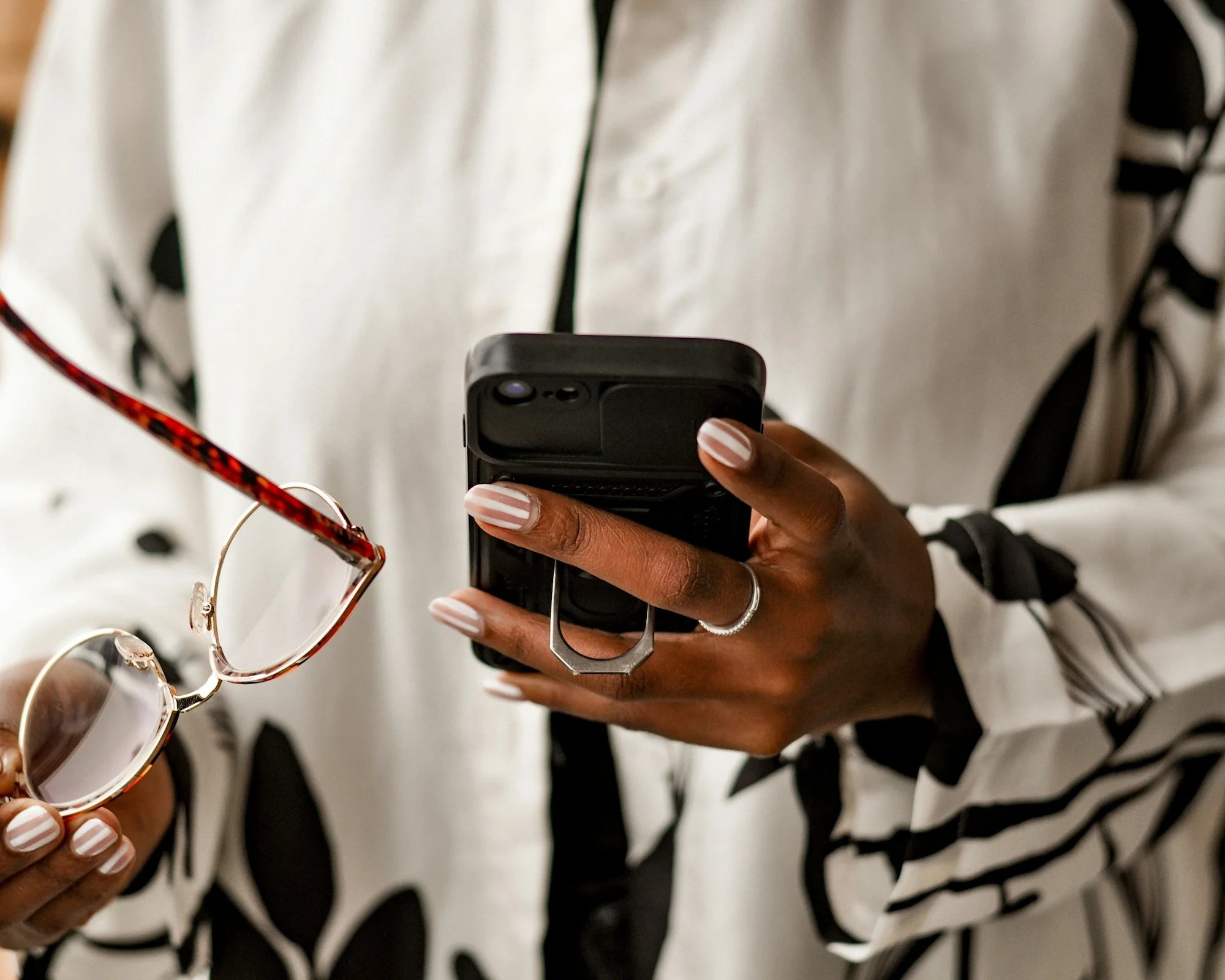 Person holding a phone and glasses wearing a patterned shirt