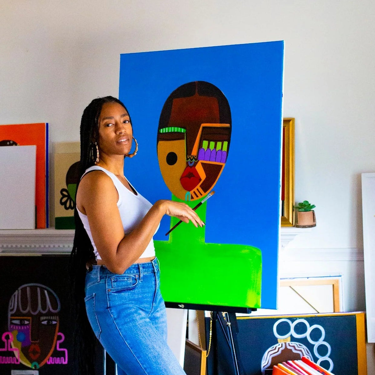 Artist Kristen Woollery standing next to one of her colourful abstract paintings in her home.